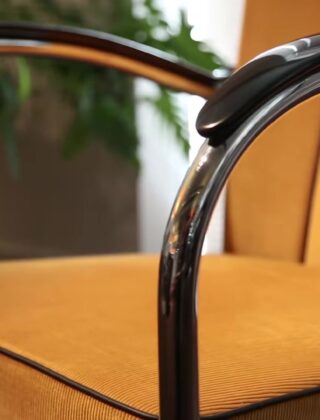 Gispen 412 fauteuil met verchroomd buisframe, zwarte armleuningen en oker ribstof