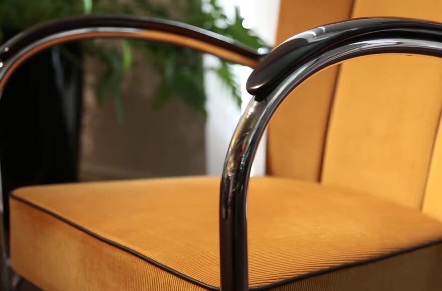 Gispen 412 fauteuil met verchroomd buisframe, zwarte armleuningen en oker ribstof