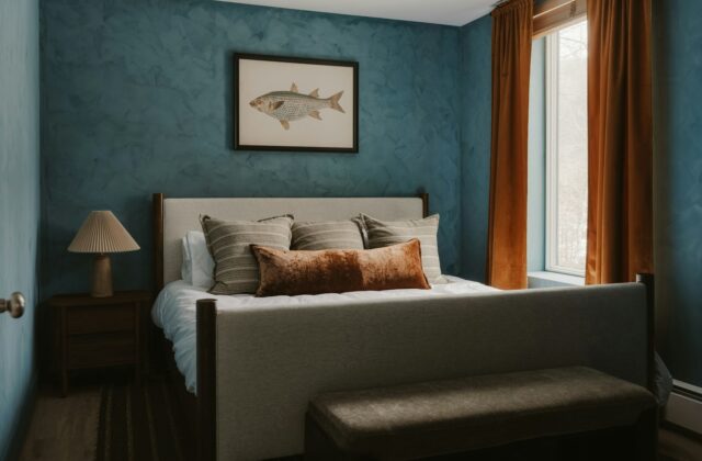 Slaapkamer met een lichtblauwe muur, houten nachtkastje en linnen beddengoed