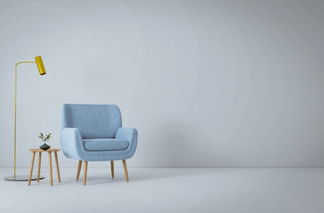 Fauteuil met voetenbank en een leeslamp naast een raam met een boekenkast erachter