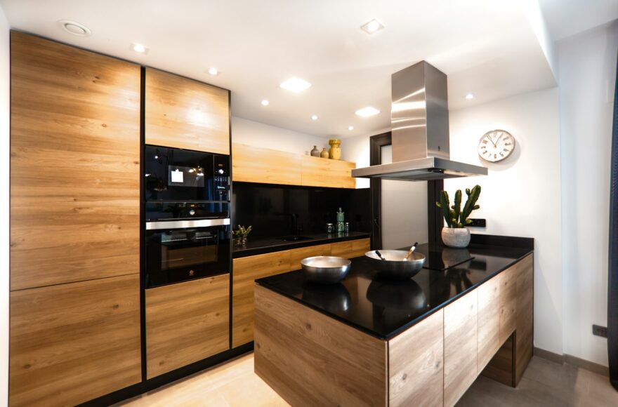 Keuken met houten tafel, open plank met aardewerk en een tafellamp op het aanrecht