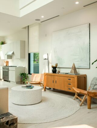 Woonkamer met donkergroene muur, fluwelen fauteuil, messing lamp en ronde spiegel