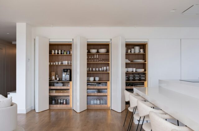 Een voorraadkast met open deuren en een koffiehoek met kopjes en glazen