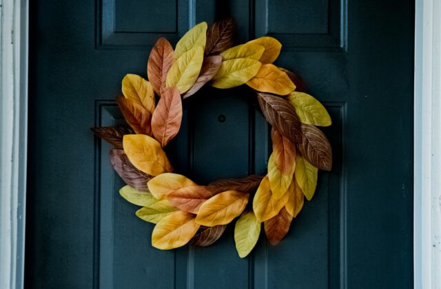 Voordeur met potten met groen, een lantaarn en een herfstkrans