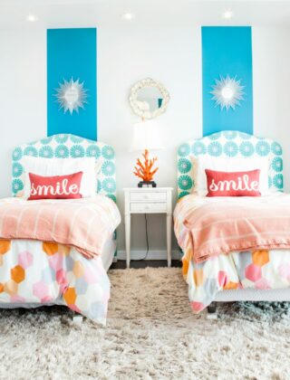 Kinderkamer met twee bedden, elk met een eigen lampje en plank
