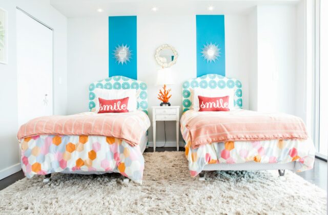 Kinderkamer met twee bedden, elk met een eigen lampje en plank