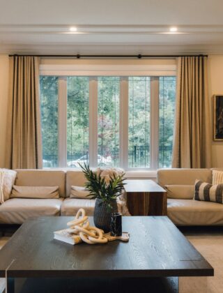 Lange linnen gordijnen die vanaf het plafond tot net boven de vloer hangen in een lichte woonkamer