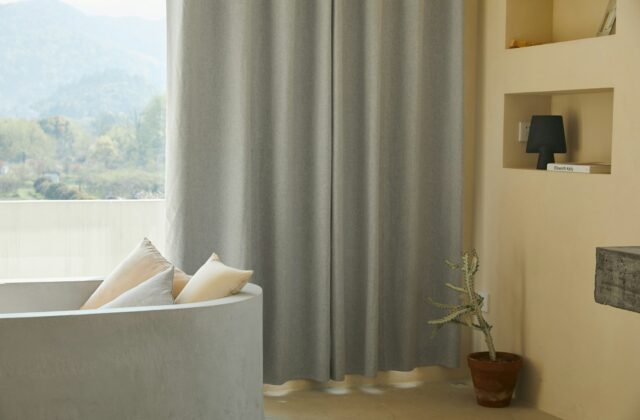 Zware linnen gordijnen voor een raam in een woonkamer met daglicht