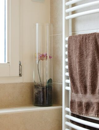 Witte handdoekradiator met opgevouwen handdoeken in een lichte badkamer met tegels