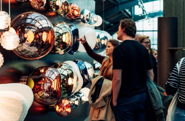 Bezoekers bekijken een wand met spiegelende hanglampen in Design Post Köln