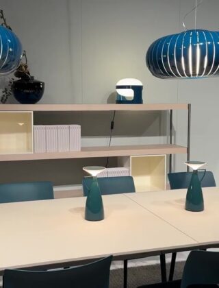 Stand met eettafel, blauwe hanglampen en open kast op Salone del Mobile in Milaan
