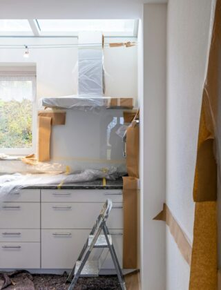 Half verbouwde keuken met kale wand, losse kastdelen en gereedschap op de vloer