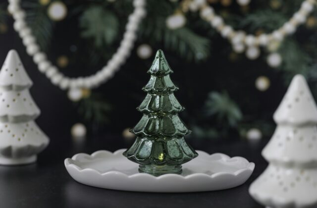 Een groene keramieken kerstboom met gekleurde lichtjes