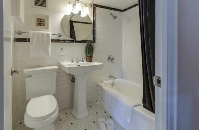 Kleine badkamer met witte wandtegels, een wastafel op poten en een messing kraan