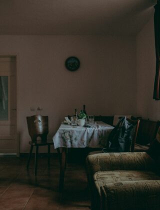 Oude witte ledenradiator onder een raam in een woonkamer met houten vloer