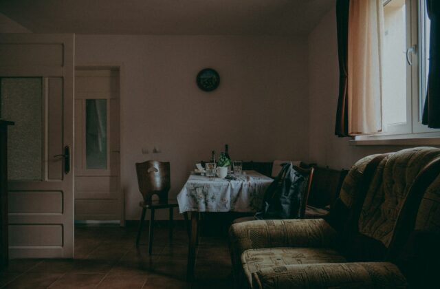 Oude witte ledenradiator onder een raam in een woonkamer met houten vloer