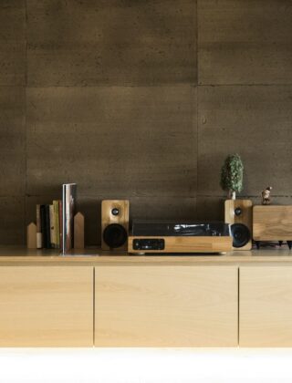 Platenspeler op een houten dressoir naast een kast met platen en een fauteuil