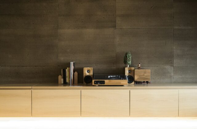 Platenspeler op een houten dressoir naast een kast met platen en een fauteuil