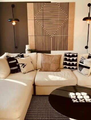 Wandlamp met warm licht naast een bank tegen een lichte muur