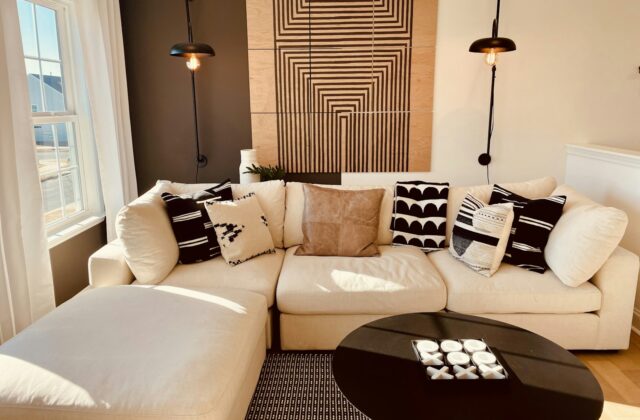 Wandlamp met warm licht naast een bank tegen een lichte muur