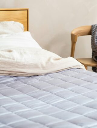Een bed opgemaakt met een gestikte quilt in een warme kleur