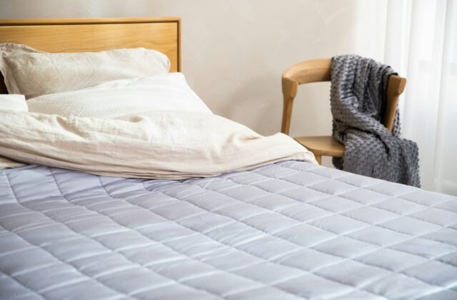 Een bed opgemaakt met een gestikte quilt in een warme kleur