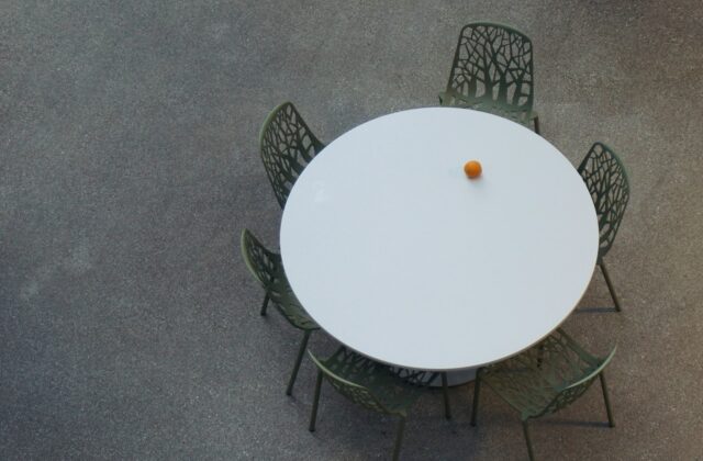 Ronde houten eettafel met stoelen en een hanglamp in een lichte eethoek