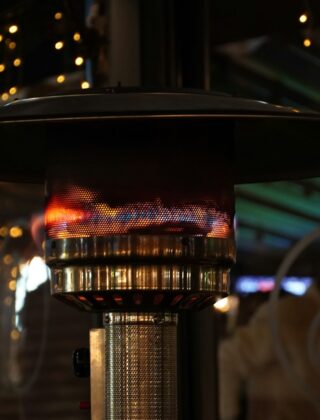 Infrarood terrasverwarmer aan de wand van een veranda met tafel en stoelen in de avond