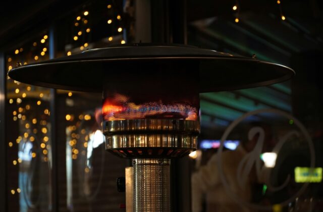 Infrarood terrasverwarmer aan de wand van een veranda met tafel en stoelen in de avond