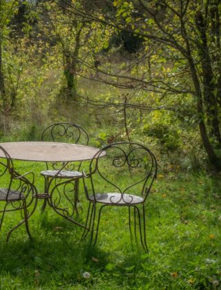 Houten tuinset op een terras met herfstbladeren en een opgevouwen beschermhoes