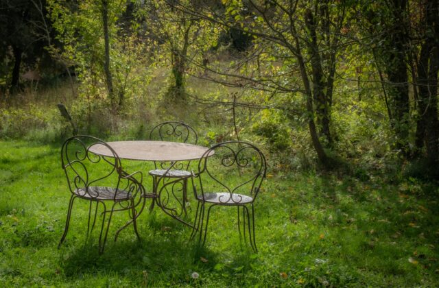 Houten tuinset op een terras met herfstbladeren en een opgevouwen beschermhoes