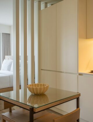 Lichte studio met een opgemaakt bed achter een open kast en een zithoek ervoor