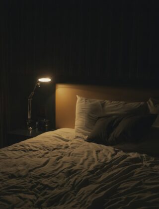 Rustige slaapkamer met een groot vloerkleed onder het bed, twee lampjes en gordijnen tot de vloer